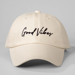 Close-up of Good Vibes black embroidery on a beige canvas baseball cap with fine stitching