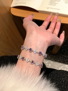 Close-up of stacked zircon flower bracelets with purple stones on woman wrist