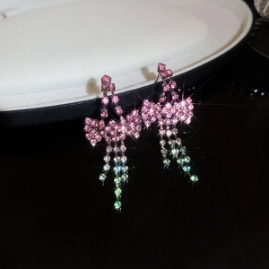 Macro shot of silver needle earrings with pink rhinestone bows and gradient tassels