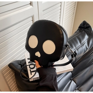 Detail of creative skull-shaped crossbody bag with white eye patches and silver zipper