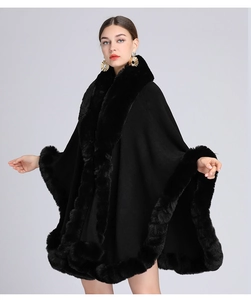 Elegant black knit poncho with faux rabbit fur collar trim on a studio model