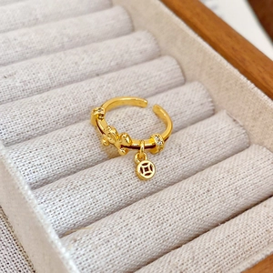 Detailed macro view of gold-plated open ring featuring a dangling ancient coin pendant