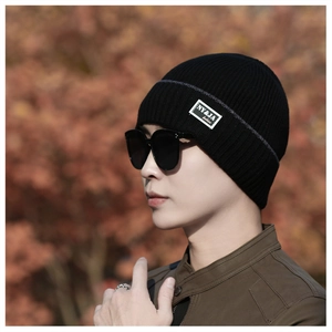 Outdoor shot of a man wearing a thick black ribbed knit beanie with a stylish side tag