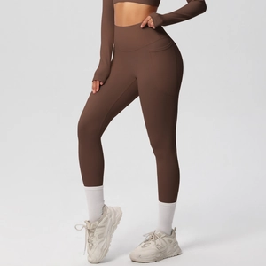 Detail of high-waist dark brown yoga leggings with functional side pockets and elastic fabric