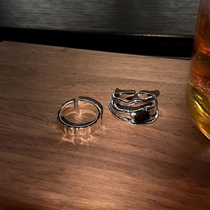 Macro detail of geometric silver rings with black zircon on rustic wooden background