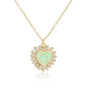 Macro shot of gold heart necklace with green enamel smiley face and zircon border