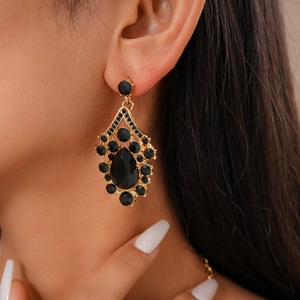 Close-up of a model wearing vintage gold drop earrings with large black rhinestones