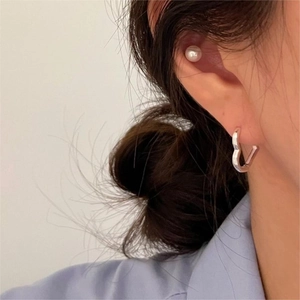 Close-up of minimalist 925 sterling silver heart hoop earrings and pearl studs on model