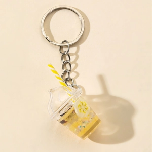 Close-up of yellow glowing milk tea cup keychain with fruit slices and striped straw
