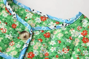 Close-up of floral print cotton jacket with blue piping and brown four-hole button