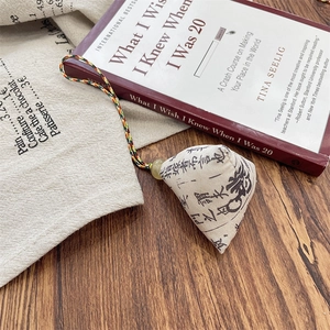 Detail of a handmade fabric Zongzi charm with a jade bead and braided lanyard on wood