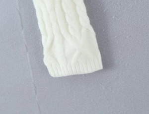 Close-up of white cable knit texture and ribbed cuff on a knitted skirt set