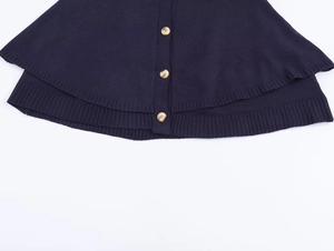 Detail of dark blue knit cardigan with marble buttons and textured cape hemline