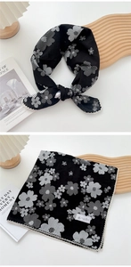 Detail of floral black neck scarf with white petal patterns and delicate lace edges