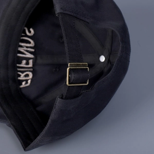 Close-up of black cotton baseball cap showing vintage metal buckle and internal embroidery