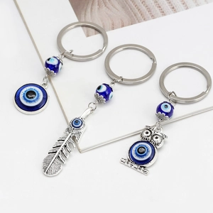 Set portachiavi malocchio argento con ciondoli a forma di gufo e piuma su sfondo bianco