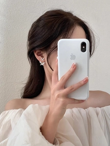 Close-up of double-layered butterfly earrings in white acrylic on a model's ear