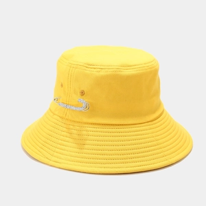 Close-up of a yellow cotton bucket hat featuring a decorative sparkling rhinestone pin
