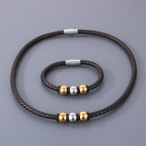 Detail of brown braided leather bracelet and necklace set with gold and silver metal beads