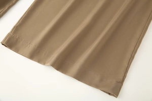 Détail du pantalon en satin marron café montrant l'ourlet et la texture du tissu