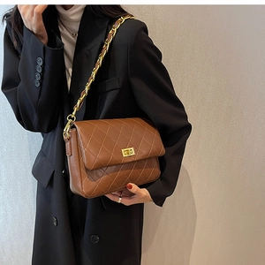 Detail of brown quilted shoulder bag with gold chain strap and turn-lock closure