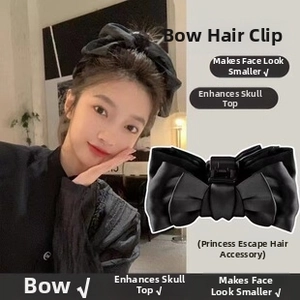 Detail of a large black satin bow hair clip on a model to enhance hair volume and style
