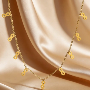 Close-up of golden infinity symbol pendant necklace on elegant champagne satin fabric