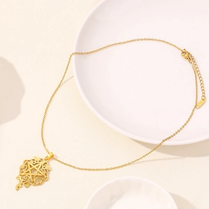 Macro detail of gold stainless steel necklace with hollow star pendant on ceramic plate
