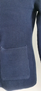 Detail showing the dark blue knitted fabric with waffle texture and a functional patch pocket
