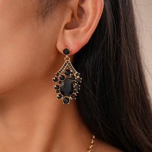 Macro shot of vintage teardrop earrings with black gems and golden alloy metal texture