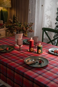 Dettaglio di candele festive rosse e verdi su una classica tovaglia natalizia a quadretti