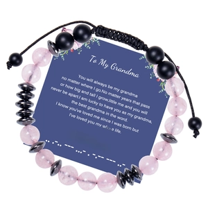 Detail of Morse code bracelet with pink crystal and black beads on a message card