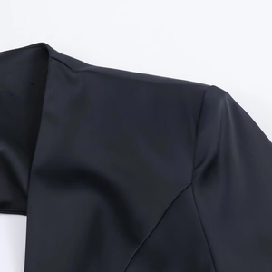 Détail de la robe mini ballon noire montrant les coutures d'épaule et le tissu brillant