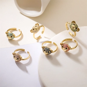 Detailed view of six gold rings with colorful micro-set bear motifs on white marble base