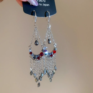 Detailed close-up of retro silver tassel earrings with red crystal beads and leaf design