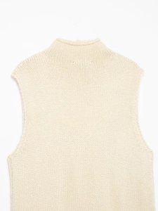 Detailed close-up of cream knit vest neckline and shoulder ribbing textures