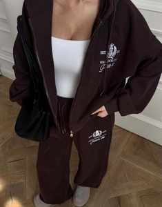 Détail d'un survêtement marron foncé avec broderie de lettres sur le sweat et le pantalon