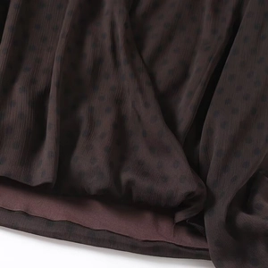 Detail aus dunkelbraunem Chiffon mit Polka Dots, Plissee-Textur und feinen Nähten