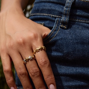 Detail of star-shaped 18K gold stainless steel open rings on a model wearing denim