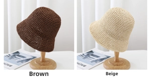 Detail view of woven straw bucket hats in brown and beige on wooden display stands