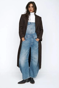 Detail of vintage washed blue denim wide-leg overalls paired with a long brown checkered coat
