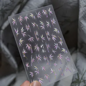 Macro detail of iridescent purple and gold bamboo nail decals with a metallic finish