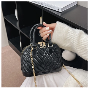 Close-up of black jelly bag with gold chain strap and quilted V-pattern texture