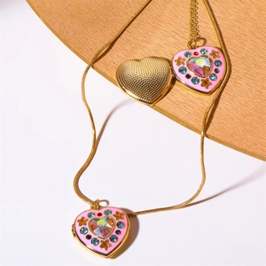Detailed macro of pink heart-shaped locket pendant on golden chain jewelry