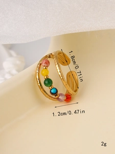 Detailed view of hammered gold ring with colorful beads on jewelry stand