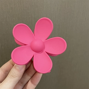 Primer plano de una pinza para el pelo con flor rosa y acabado mate en la mano