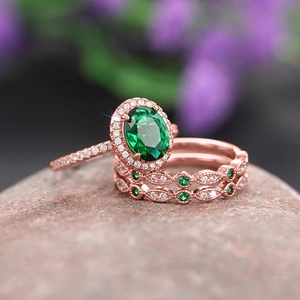 Detailed macro view of three-piece rose gold ring set with emerald oval stone and diamonds