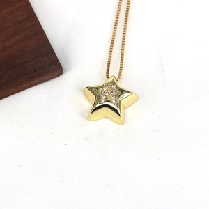 Macro view of gold star pendant with letter R rhinestone inlay on a textured background
