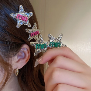 Detail of silver star metal hair clip with pink and green letter patches in Y2K style
