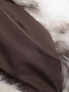 Detailed macro shot of brown woven fabric and white-grey faux fur contrast on the jacket